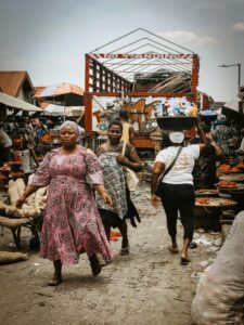 Women walk through a bustling African market, showcasing daily life and culture.